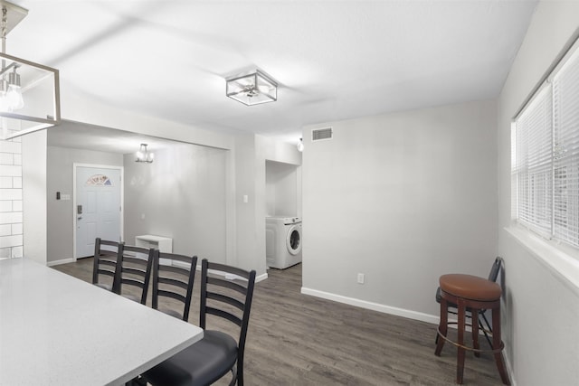 dining area with dark hardwood / wood-style floors, a chandelier, and washing machine and clothes dryer