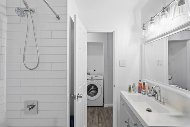 bathroom with a tile shower, hardwood / wood-style flooring, vanity, and washer / dryer