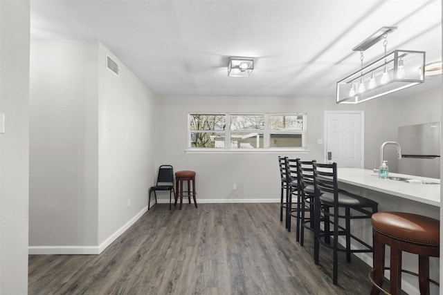 dining area featuring a textured ceiling, sink, and dark hardwood / wood-style floors