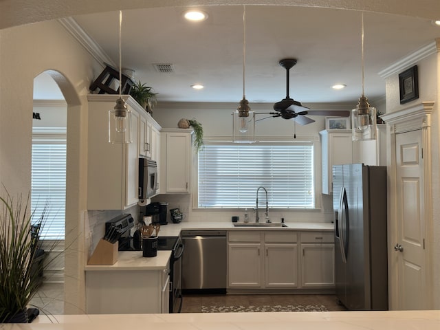 kitchen with appliances with stainless steel finishes, ceiling fan, sink, white cabinets, and hanging light fixtures