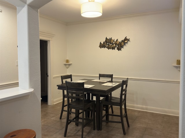 dining area with dark tile patterned floors and crown molding