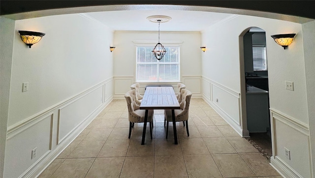 dining space with arched walkways, a decorative wall, and an inviting chandelier