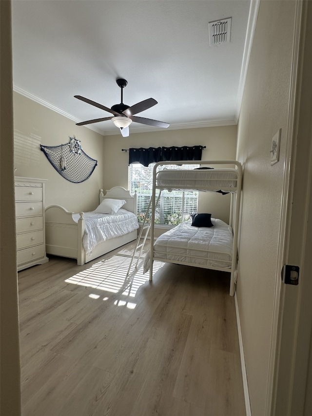 bedroom with ceiling fan, wood-type flooring, and crown molding