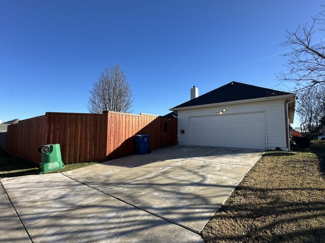 view of property exterior with concrete driveway, fence, and a chimney