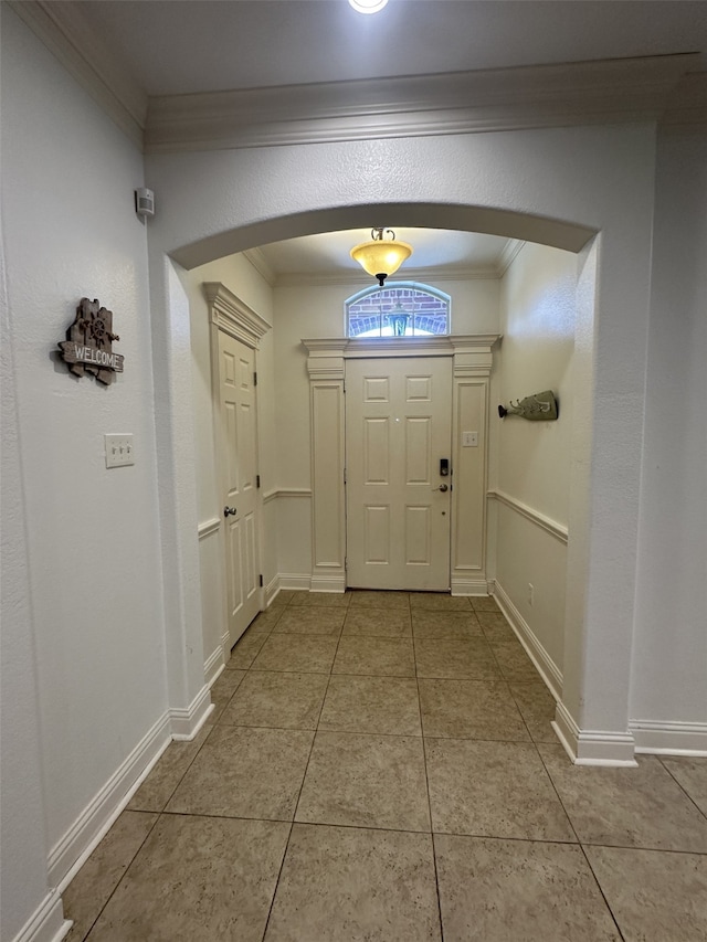 entrance foyer with tile patterned flooring and crown molding