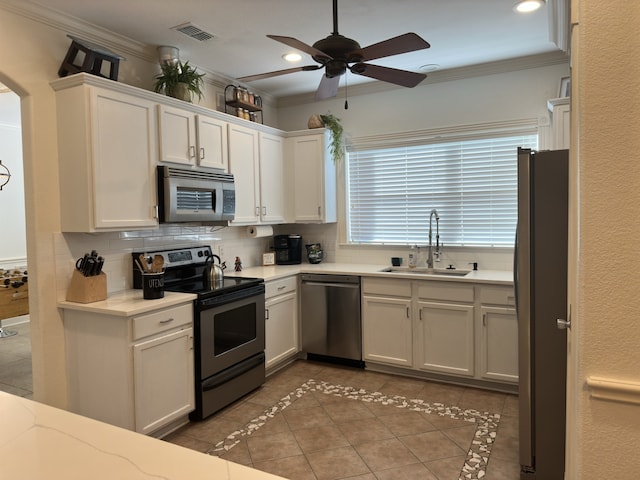 kitchen featuring sink, white cabinets, dark tile patterned flooring, and appliances with stainless steel finishes