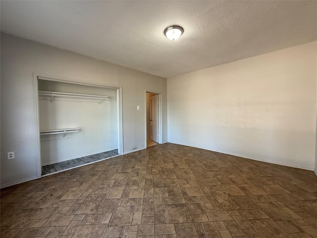 unfurnished bedroom featuring a textured ceiling and a closet