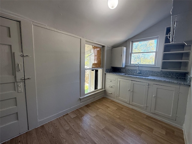 kitchen featuring white cabinetry, sink, vaulted ceiling, and light wood-type flooring