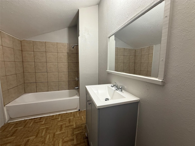 bathroom featuring vaulted ceiling, parquet floors, vanity, a textured ceiling, and washtub / shower combination