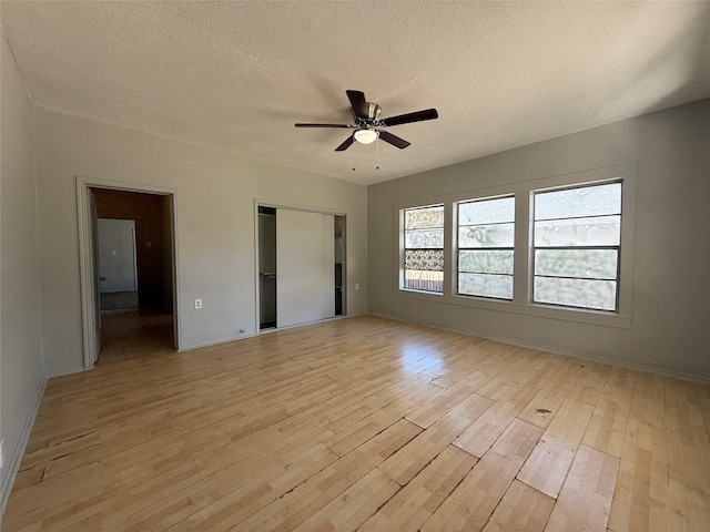 unfurnished bedroom with ensuite bath, ceiling fan, a textured ceiling, a closet, and light wood-type flooring