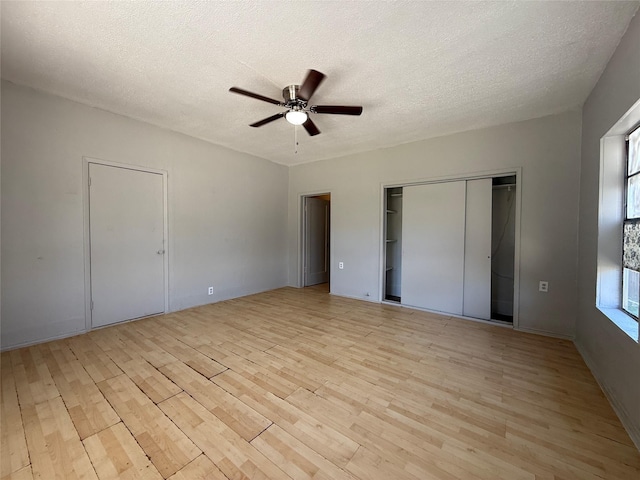 unfurnished bedroom featuring ceiling fan, a textured ceiling, light wood-type flooring, and a closet