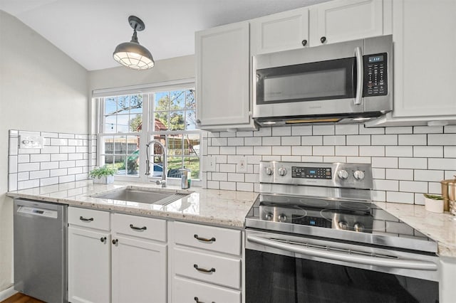 kitchen featuring appliances with stainless steel finishes, vaulted ceiling, sink, white cabinets, and hanging light fixtures