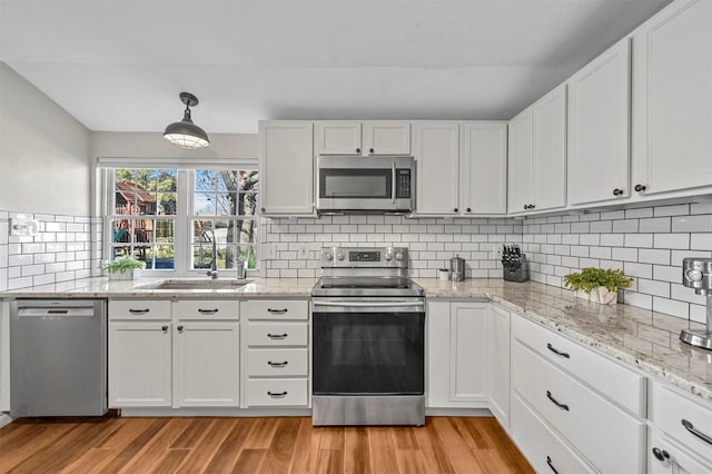 kitchen featuring white cabinetry, sink, decorative light fixtures, decorative backsplash, and appliances with stainless steel finishes