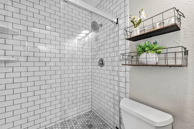 bathroom featuring a tile shower and toilet