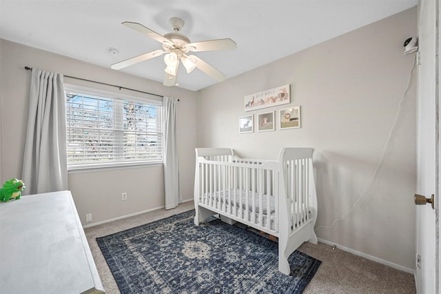 carpeted bedroom featuring ceiling fan and a nursery area