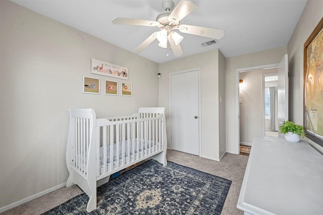 bedroom featuring carpet flooring, a nursery area, and ceiling fan