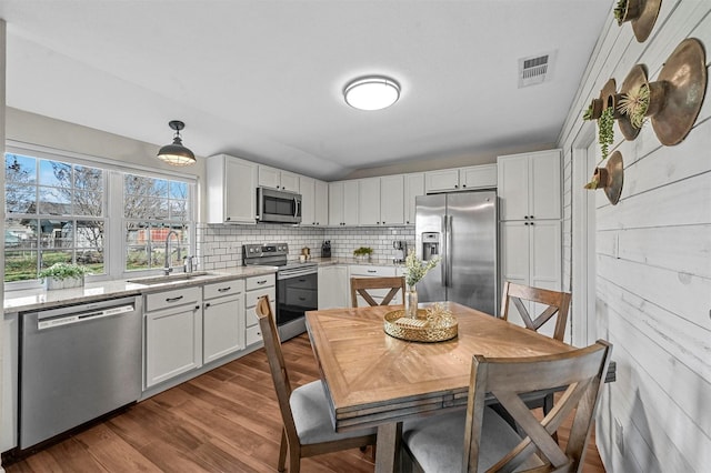 kitchen featuring white cabinets, sink, decorative backsplash, decorative light fixtures, and stainless steel appliances