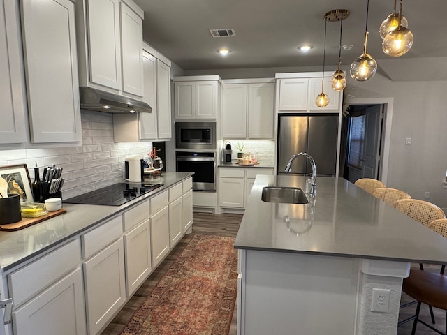 kitchen with a kitchen breakfast bar, a kitchen island with sink, sink, and appliances with stainless steel finishes