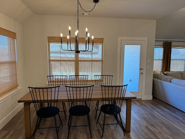 dining area featuring a healthy amount of sunlight, dark hardwood / wood-style floors, vaulted ceiling, and an inviting chandelier