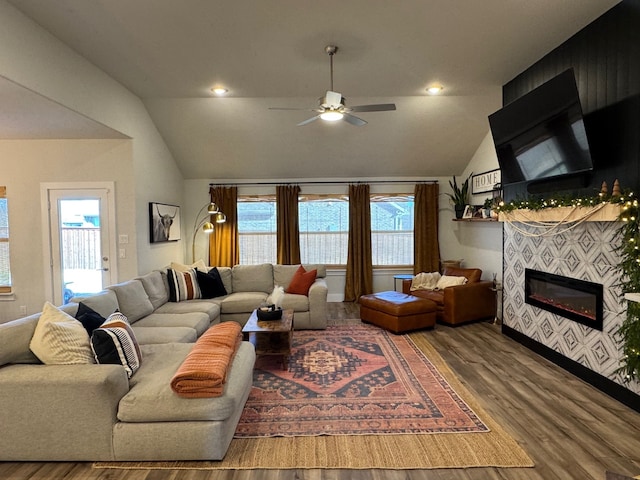 living room featuring hardwood / wood-style flooring, ceiling fan, lofted ceiling, and a tiled fireplace