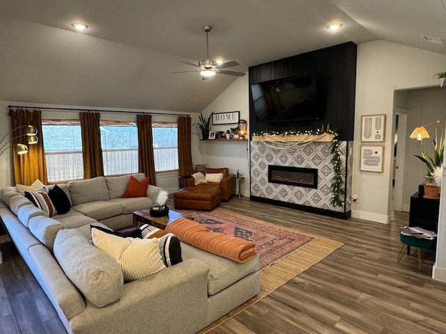 living room featuring dark hardwood / wood-style flooring, ceiling fan, a fireplace, and vaulted ceiling