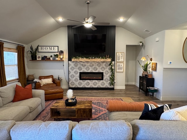 living room featuring vaulted ceiling, a tiled fireplace, ceiling fan, and dark hardwood / wood-style floors