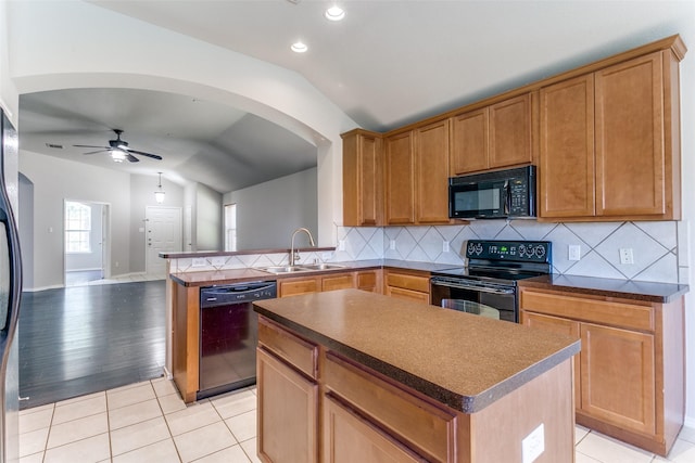 kitchen with lofted ceiling, sink, a center island, light tile patterned floors, and black appliances