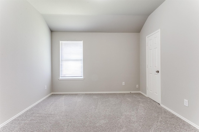 carpeted empty room with vaulted ceiling