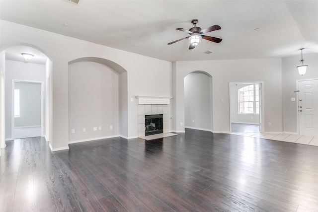 unfurnished living room featuring ceiling fan, dark hardwood / wood-style floors, and a fireplace