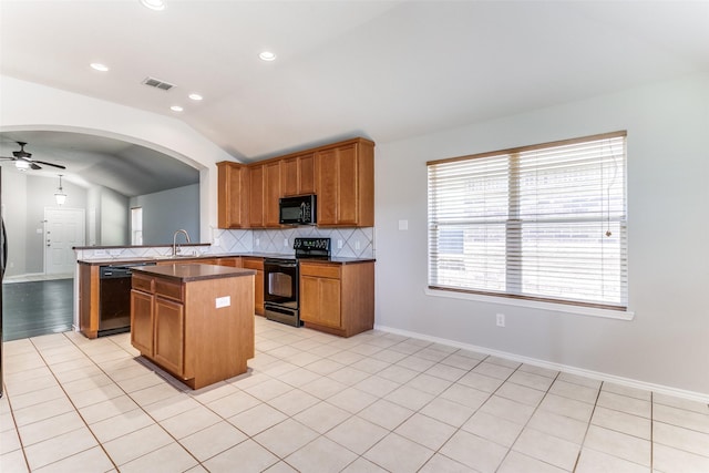 kitchen featuring a center island, vaulted ceiling, kitchen peninsula, decorative backsplash, and black appliances