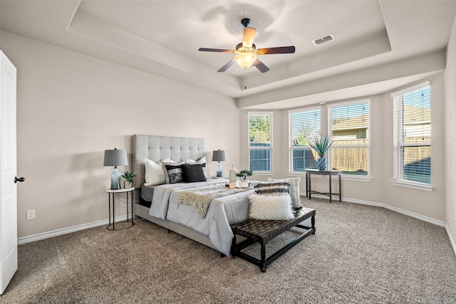 carpeted bedroom featuring a raised ceiling and ceiling fan