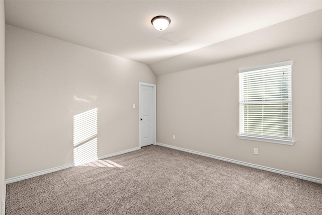 spare room featuring carpet floors and vaulted ceiling