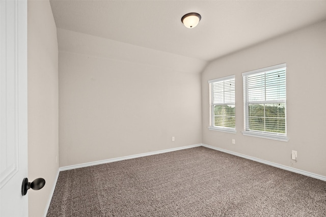 carpeted spare room with vaulted ceiling