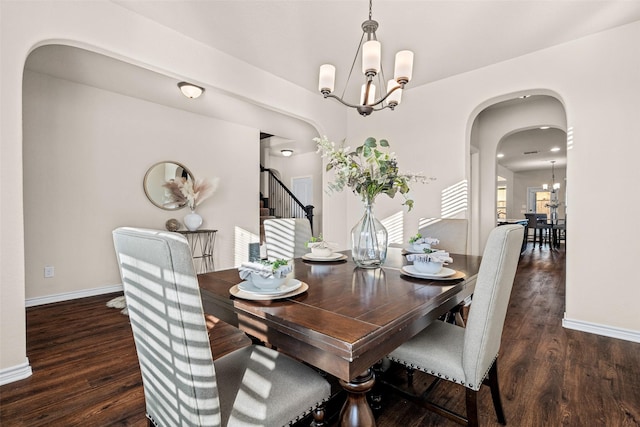 dining space featuring dark wood-type flooring and a notable chandelier