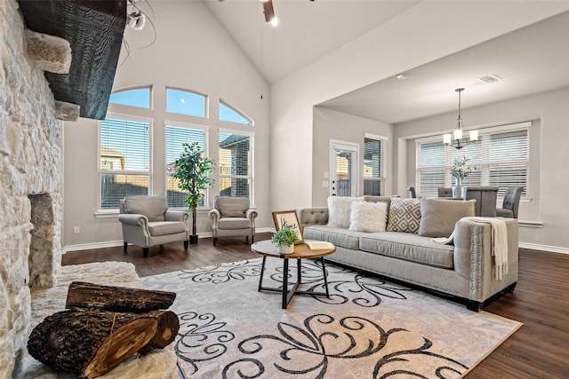 living room with plenty of natural light, dark hardwood / wood-style flooring, ceiling fan with notable chandelier, and high vaulted ceiling