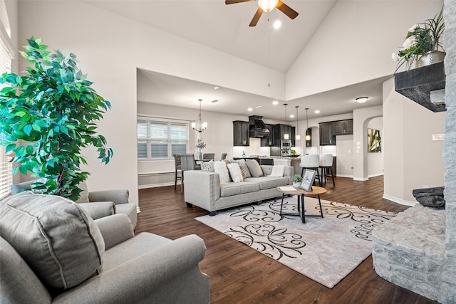 living room with dark hardwood / wood-style flooring, ceiling fan with notable chandelier, and high vaulted ceiling