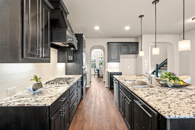 kitchen with custom range hood, stainless steel appliances, sink, decorative light fixtures, and dark hardwood / wood-style floors