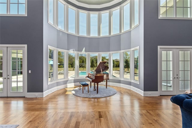 interior space with a healthy amount of sunlight, a towering ceiling, and french doors