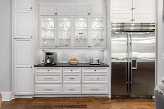 kitchen with tasteful backsplash, dark hardwood / wood-style flooring, stainless steel built in fridge, and white cabinets