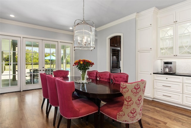 dining area with a notable chandelier, wood-type flooring, crown molding, and french doors