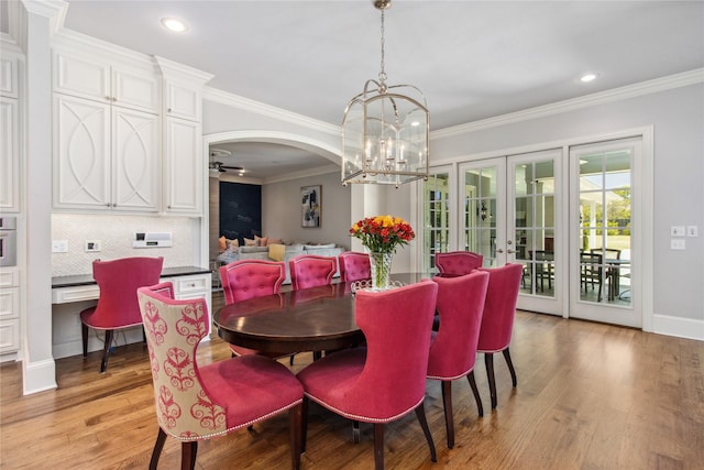 dining area featuring french doors, ceiling fan with notable chandelier, light hardwood / wood-style flooring, and ornamental molding