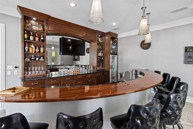 bar featuring crown molding, dark brown cabinets, and hanging light fixtures