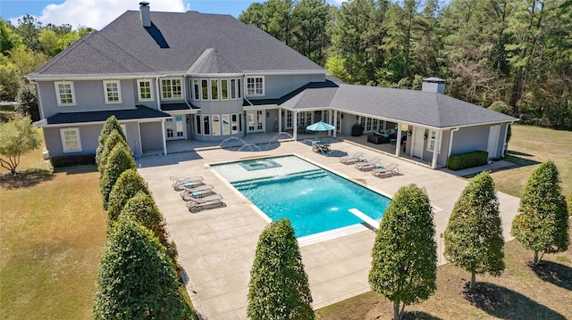 rear view of property featuring a swimming pool with hot tub and a patio area