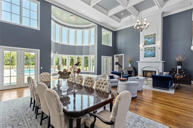 dining space with wood-type flooring, ornamental molding, a high ceiling, and french doors