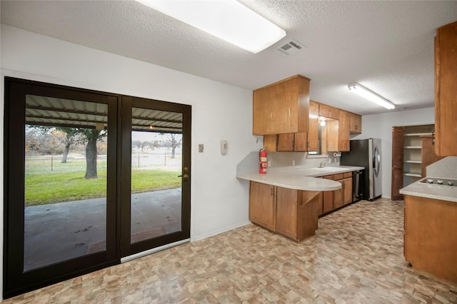 kitchen featuring black dishwasher, sink, kitchen peninsula, and a textured ceiling