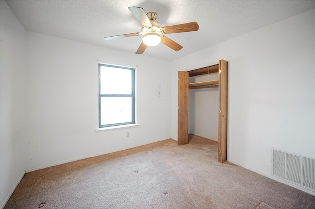 unfurnished bedroom with ceiling fan, light colored carpet, a textured ceiling, and a closet