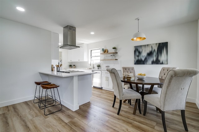 kitchen featuring kitchen peninsula, sink, dishwasher, white cabinetry, and range hood