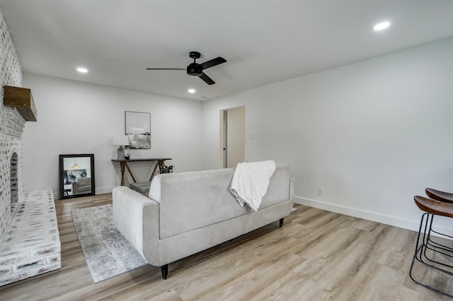 bedroom with ceiling fan, a fireplace, and light hardwood / wood-style flooring