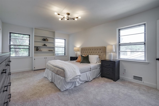 bedroom featuring light colored carpet and a notable chandelier