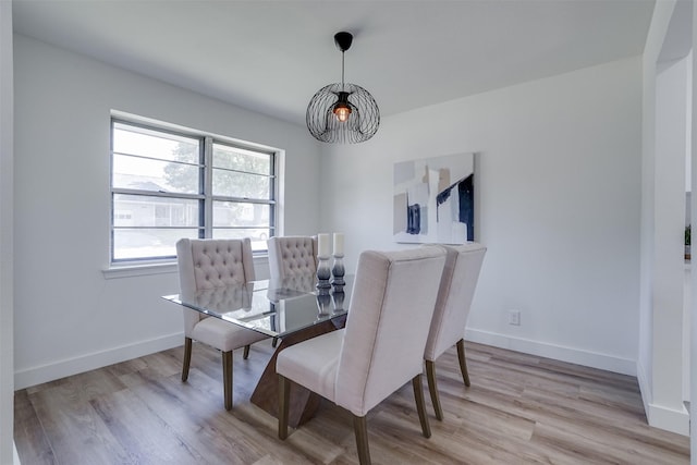 dining area with light hardwood / wood-style floors and an inviting chandelier